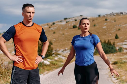 A couple is captured in a moment of relaxation and rejuvenation, taking a break after an intense morning run to recharge and enjoy the tranquility of their surroundings