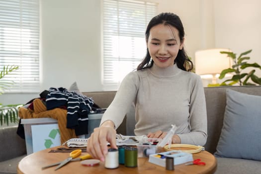 Woman recycling and upcycling clothes at home, showcasing sustainable and eco-friendly practices.