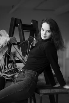 young beautiful woman posing in a black sweater near the window