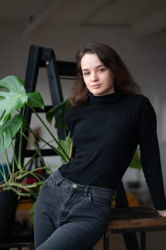 young beautiful woman posing in a black sweater near the window