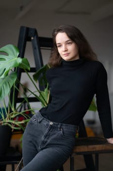 young beautiful woman posing in a black sweater near the window