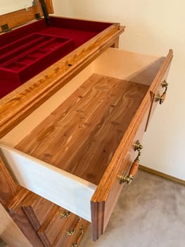 Denver, Colorado, USA-October 28, 2023-A detailed view of an open wooden dresser drawer, showcasing its smooth wooden interior and red velvet-lined compartments. The craftsmanship and elegant design make it a perfect storage solution for precious items.