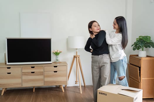 Lesbian couple moving into their new home, unpacking boxes, and decorating. Celebrating love and new beginnings in a modern, cozy living room.