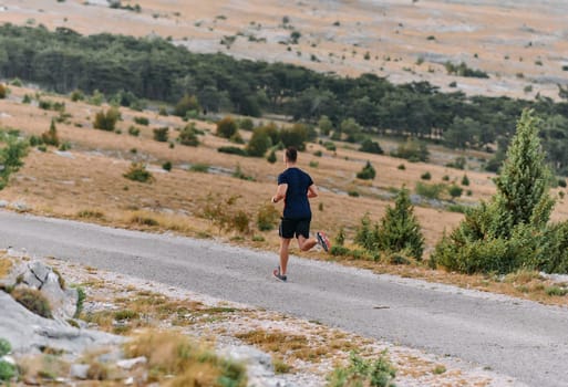 A muscular male athlete runs along a rugged mountain path at sunrise, surrounded by breathtaking rocky landscapes and natural beauty.