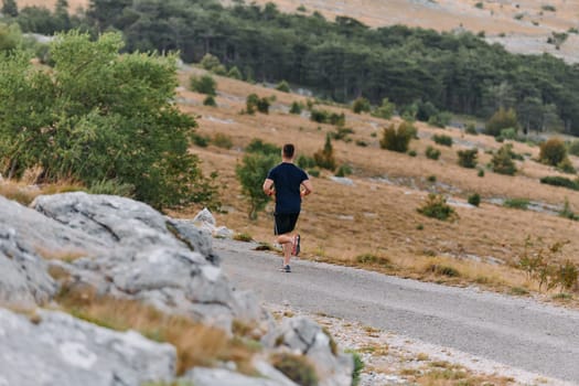 A muscular male athlete runs along a rugged mountain path at sunrise, surrounded by breathtaking rocky landscapes and natural beauty.