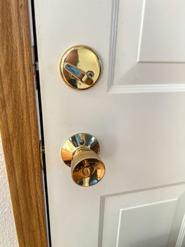 Denver, Colorado, USA-November 25, 2023-A close-up view of a polished brass door handle and matching deadbolt on a wooden door. The shiny brass fixtures add a touch of elegance and security to the doors natural wood grain.