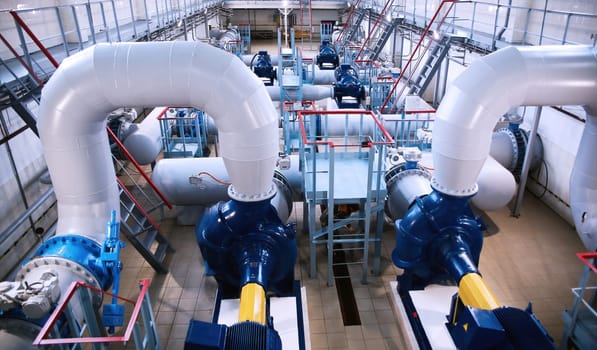 The industrial water pumping station features well-maintained pumps, pipes, and valves, brightly lit and showcasing precise engineering in efficient water management.