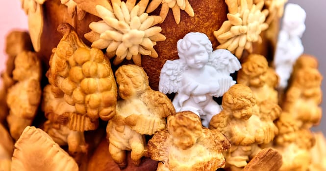 Christmas composition with a figurine of an angel made of sugar on a large pie, surrounded by angels made of dough, close-up. Focus on the foreground.