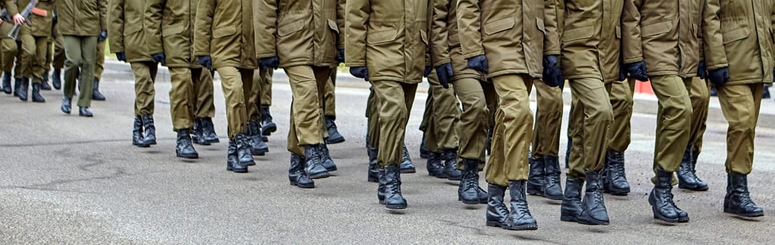 Disciplined soldiers in camouflage march in perfect synchronization during a military parade. Helmets and rifles add to the display of unity and strength, evoking pride.