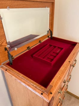 Denver, Colorado, USA-October 28, 2023-A detailed view of an open wooden dresser drawer, showcasing its smooth wooden interior and red velvet-lined compartments. The craftsmanship and elegant design make it a perfect storage solution for precious items.