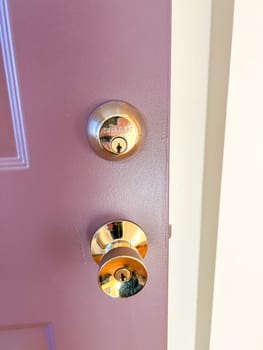 Denver, Colorado, USA-November 25, 2023-A close-up view of a polished brass door handle and matching deadbolt on a wooden door. The shiny brass fixtures add a touch of elegance and security to the doors natural wood grain.