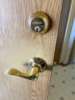 Denver, Colorado, USA-November 25, 2023-A close-up view of a polished brass door handle and matching deadbolt on a wooden door. The shiny brass fixtures add a touch of elegance and security to the doors natural wood grain.