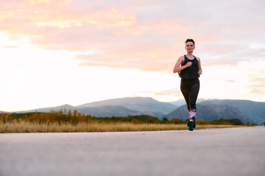 A determined athlete runs confidently under the sun, surrounded by stunning natural scenery, showcasing strength and resilience in her pursuit of fitness