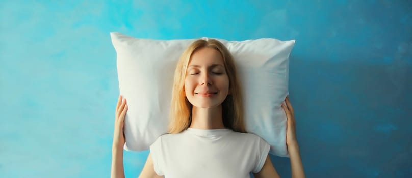 Healthy sleep, happy relaxed sleepy young woman on white soft comfortable pillow imagining that she is lying on the bed