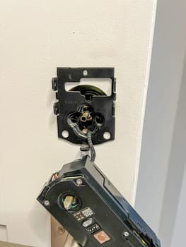 A close-up image showing the process of fixing a digital entrance lock on the entry door of a house. The lock mechanism is partially installed, highlighting the intricate details of the installation.