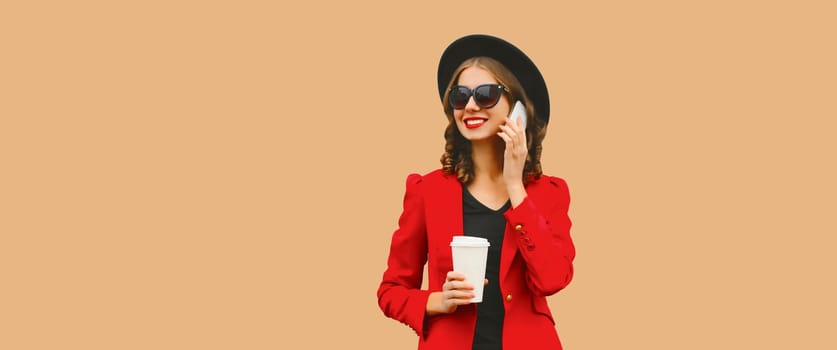 Beautiful lady woman calling on smartphone in red business suit, black hat isolated on brown studio background, copy space for advertising text