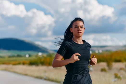 A determined athlete runs confidently under the sun, surrounded by stunning natural scenery, showcasing strength and resilience in her pursuit of fitness