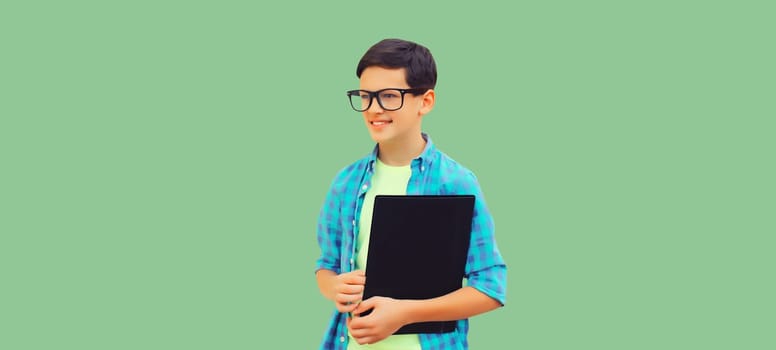 Portrait of happy smiling teenager boy in eyeglasses with folder or book on green background