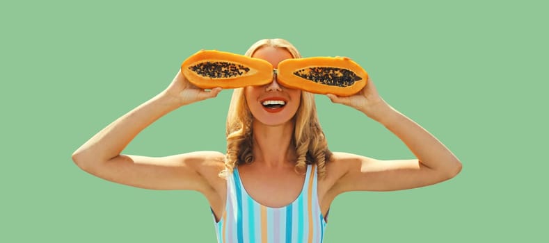 Summer portrait of happy cheerful laughing young woman posing with juicy papaya fruit on green background