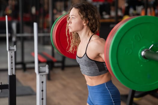 Middle-aged woman doing squats with a barbell in the gym