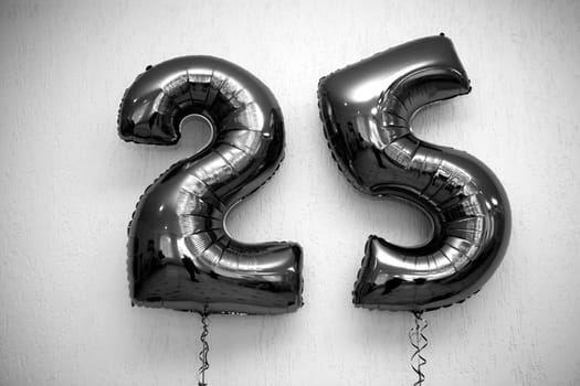 Two stunning black shiny number 25 balloons on a solid white background, adding elegance to any birthday or anniversary celebration. Ideal for party decorations and festive occasions.