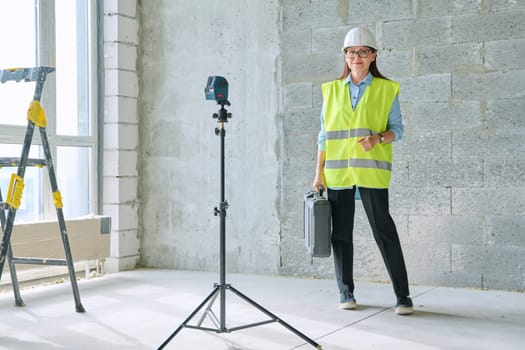 Portrait of woman industrial worker builder engineer architect supervisor at construction. Confident female in vest helmet with bag of equipment looking at camera. Construction technical professions