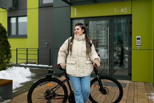 A woman is seen walking her bike in the midst of a snow-covered path. She carefully navigates the icy terrain, pushing her bike alongside her as she makes her way through the winter landscape.