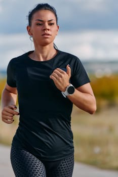 A determined athlete runs confidently under the sun, surrounded by stunning natural scenery, showcasing strength and resilience in her pursuit of fitness