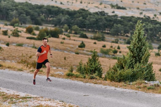 A muscular male athlete runs along a rugged mountain path at sunrise, surrounded by breathtaking rocky landscapes and natural beauty.