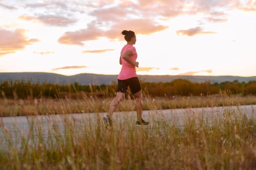 A determined athlete runs confidently under the sun, surrounded by stunning natural scenery, showcasing strength and resilience in her pursuit of fitness