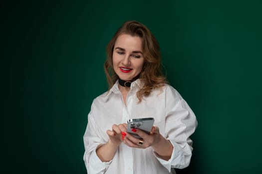 A woman wearing a white shirt is seen holding a cell phone in her hand.