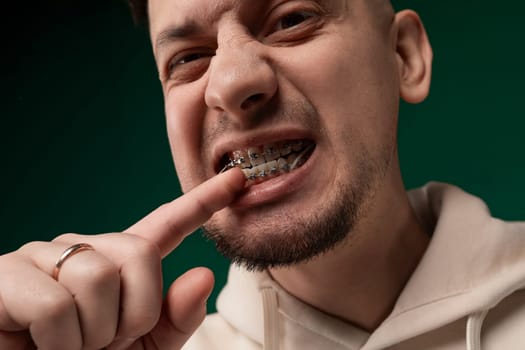 A man stands with a toothbrush in his mouth, brushing his teeth with a focused expression. He holds the toothbrush with one hand, moving it in circular motions.