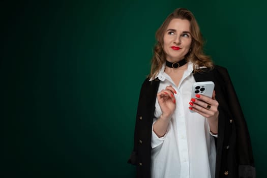 A woman wearing a white shirt is seen holding a cell phone in her hand, focusing on the screen intently. She appears engaged in a conversation or browsing content on the device.