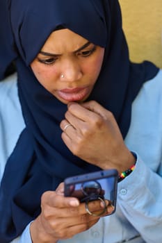 A close-up portrait captures the engagement of a Middle Eastern teenage Muslim girl in her digital world, as she uses a smartphone with focused attention