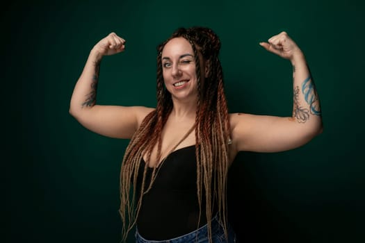 A woman with dreadlocks is striking a pose in front of the camera, showcasing her unique hairstyle. She exudes confidence and style as she stands for the photograph.