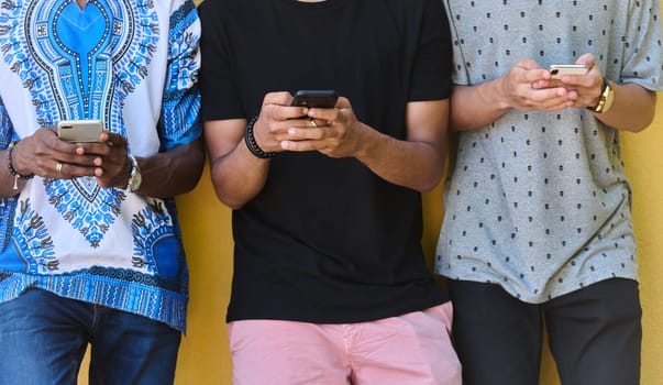 A diverse group of teenagers standing together against a wall, engrossed in their smartphones, showcasing modern connectivity and social interaction.