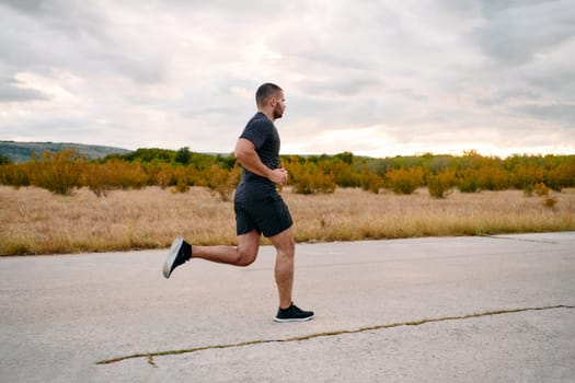 An athletic man jogs under the sun, conditioning his body for life's extreme challenges, exuding determination and strength in his preparation for the journey ahead