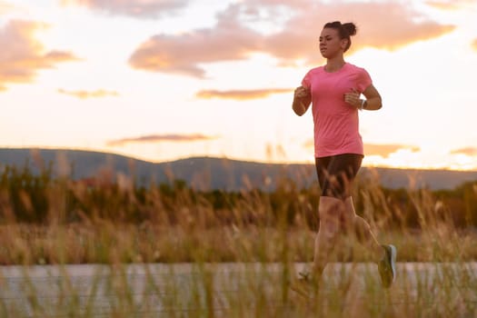 A determined athlete runs confidently under the sun, surrounded by stunning natural scenery, showcasing strength and resilience in her pursuit of fitness