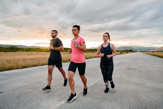 In a breathtaking scene of nature's beauty, an athlete leads a group run at sunset, inspiring and motivating her companions with her leadership and determination