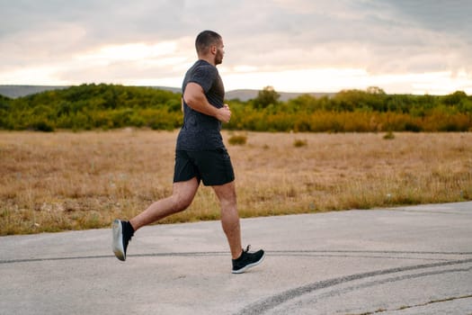 An athletic man jogs under the sun, conditioning his body for life's extreme challenges, exuding determination and strength in his preparation for the journey ahead