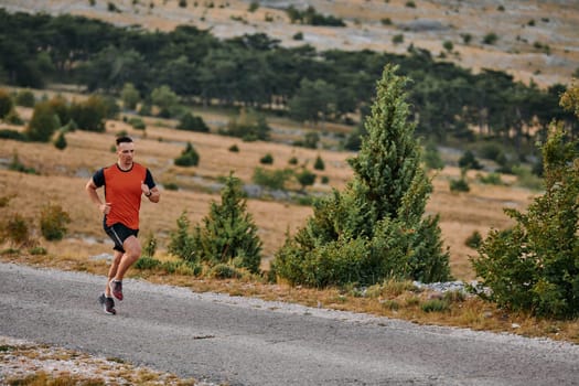 A muscular male athlete runs along a rugged mountain path at sunrise, surrounded by breathtaking rocky landscapes and natural beauty.