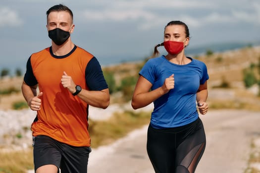 Couple running in nature at morning wearing protective face masks.