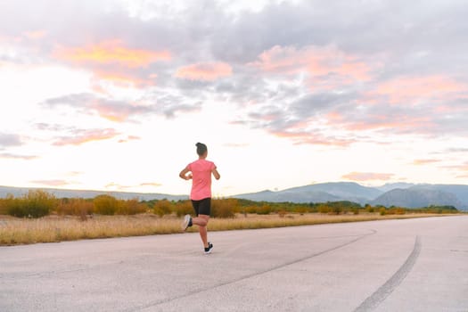 A determined athlete runs confidently under the sun, surrounded by stunning natural scenery, showcasing strength and resilience in her pursuit of fitness