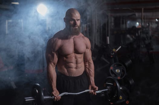 Caucasian bald topless man doing an exercise with a barbell in the gym. Bicep curls with weights