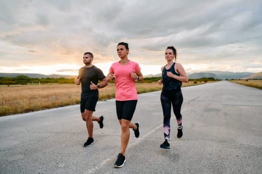 In a breathtaking scene of nature's beauty, an athlete leads a group run at sunset, inspiring and motivating her companions with her leadership and determination