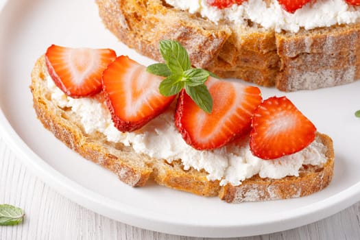 Homemade Crispbread toast with Cottage Cheese and Strawberry on white wooden board.