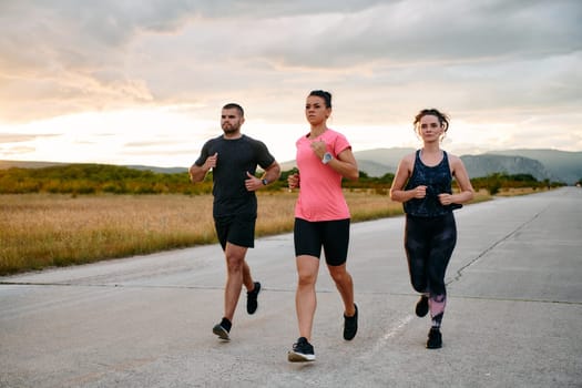 In a breathtaking scene of nature's beauty, an athlete leads a group run at sunset, inspiring and motivating her companions with her leadership and determination