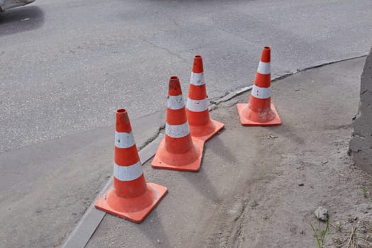 Photo orange cones standing on a gray sidewalk. Traffic and road works.
