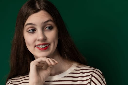 A woman wearing a striped shirt is striking a pose for a picture. She stands confidently, smiling at the camera with her hands on her hips, while showcasing her stylish outfit.
