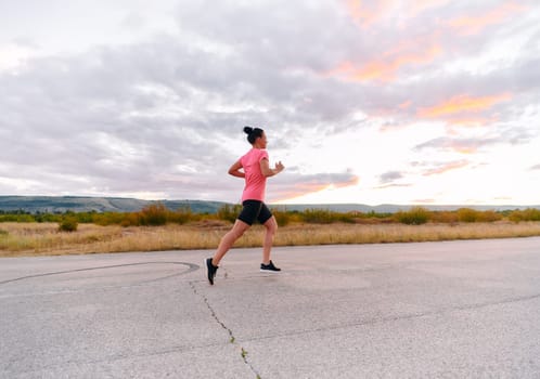 A determined athlete runs confidently under the sun, surrounded by stunning natural scenery, showcasing strength and resilience in her pursuit of fitness